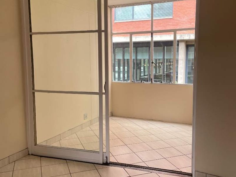 An empty, enclosed balcony or sunroom featuring tiled flooring and large sliding glass doors, providing a bright and versatile transition space.