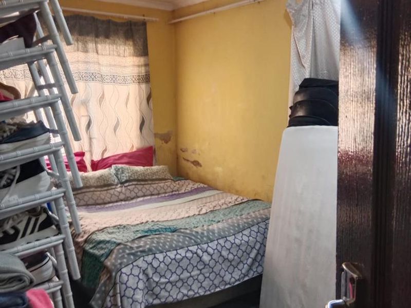 A bedroom featuring yellow walls with visible surface damage and peeling paint, requiring cosmetic attention and refurbishment.