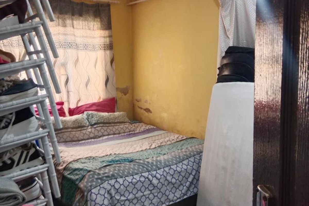 A bedroom featuring yellow walls with visible surface damage and peeling paint, requiring cosmetic attention and refurbishment.