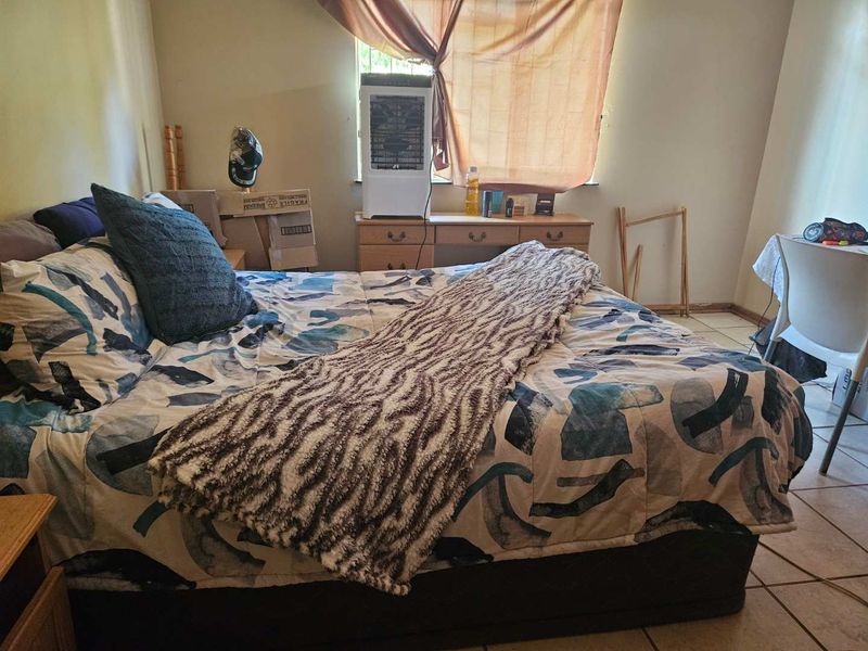 A bedroom featuring tiled flooring and a window, providing a functional space for rest.