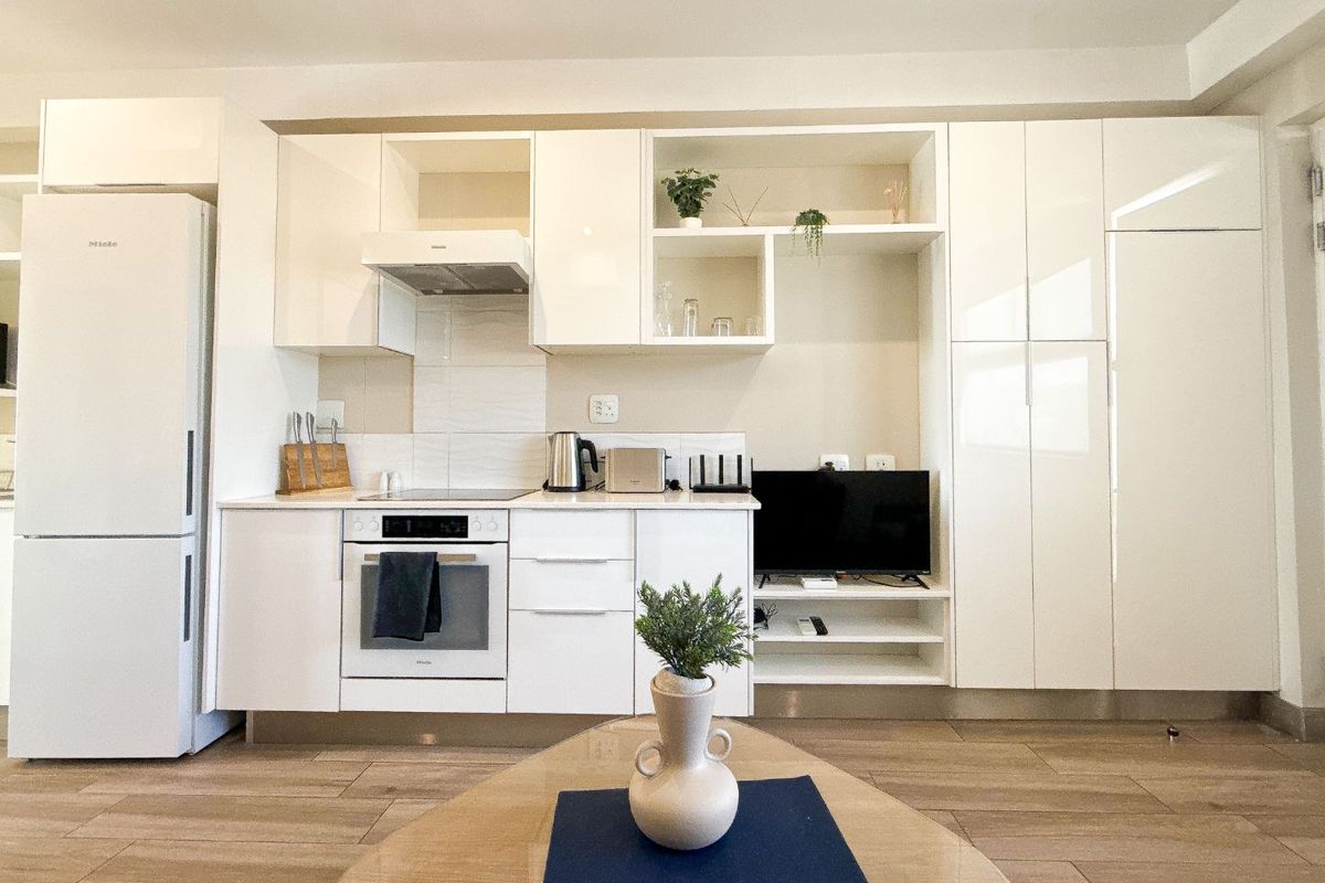 Modern open-plan kitchen featuring high-gloss white cabinetry, integrated appliances, and sleek stone countertops, seamlessly integrated into the living space.
