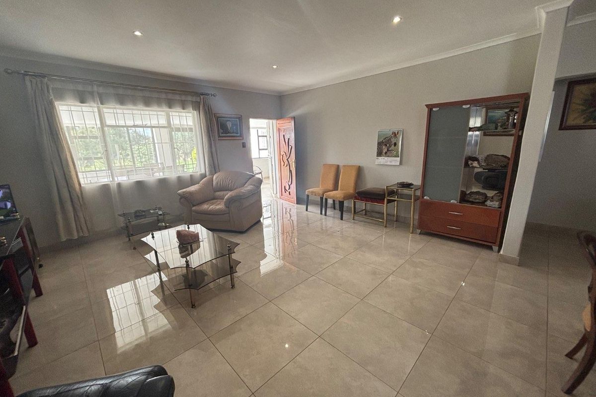 Spacious living area featuring large format floor tiles, recessed downlighting, and a large window providing natural light.