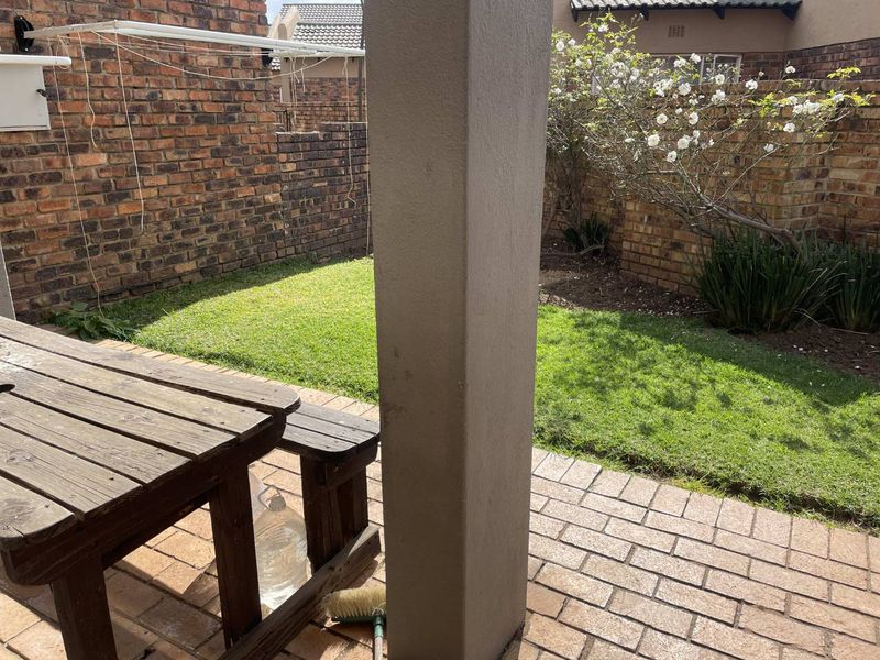 A private rear garden featuring a paved patio area, a small lawn, and perimeter brick boundary walls.