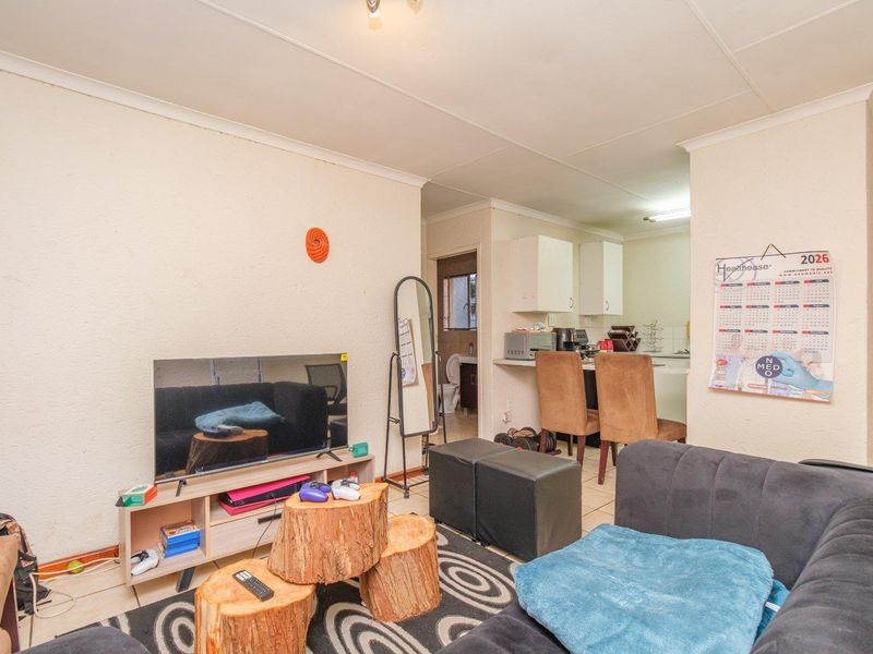 Open plan living area featuring tiled flooring and a functional kitchen with a breakfast counter, providing a versatile space for daily living.