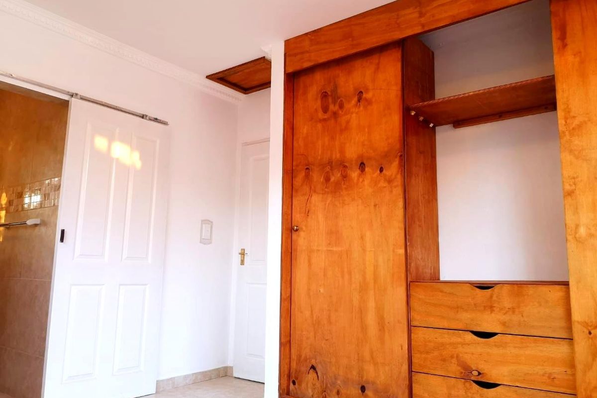 A bedroom interior featuring built-in wooden cabinetry with integrated drawers and shelving, complemented by white panel doors and crown molding.