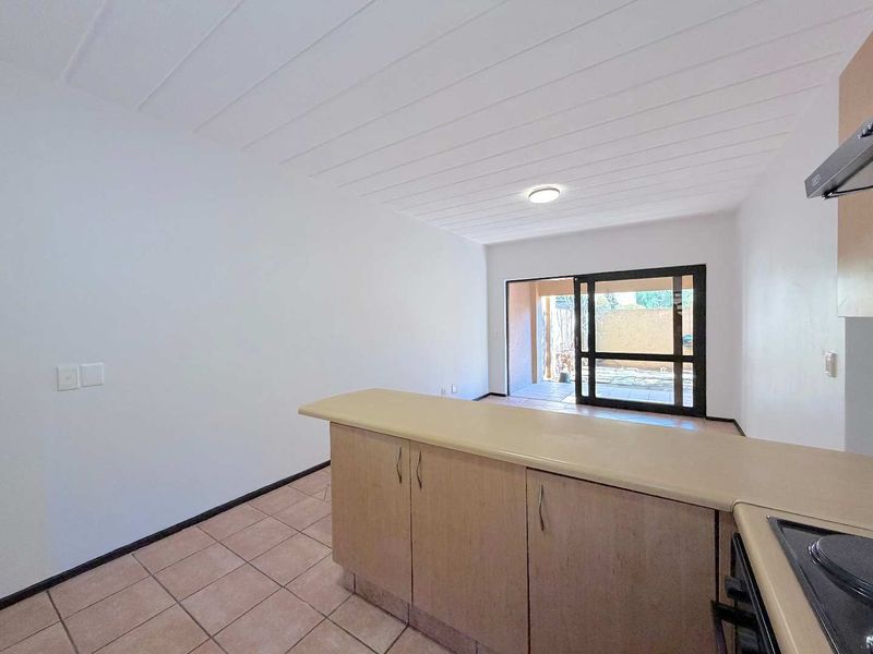 Open plan kitchen area featuring built-in cabinetry, tiled flooring, and a sliding glass door leading to an outdoor patio space.