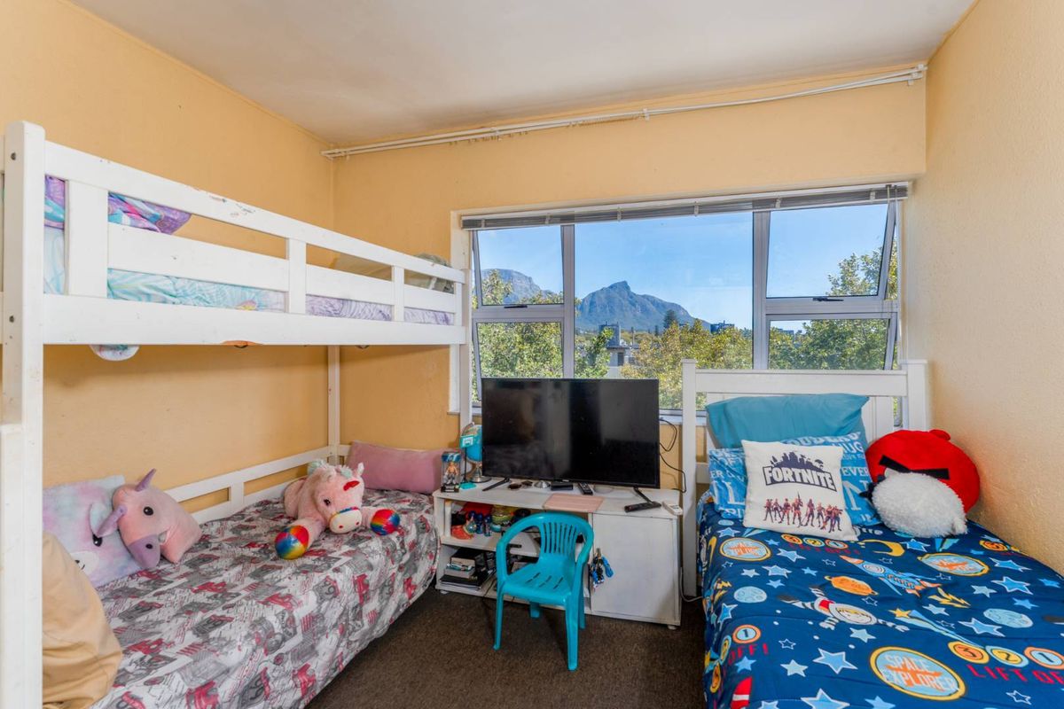 A bedroom featuring large windows with mountain views, providing natural light and a functional layout for a child's room.
