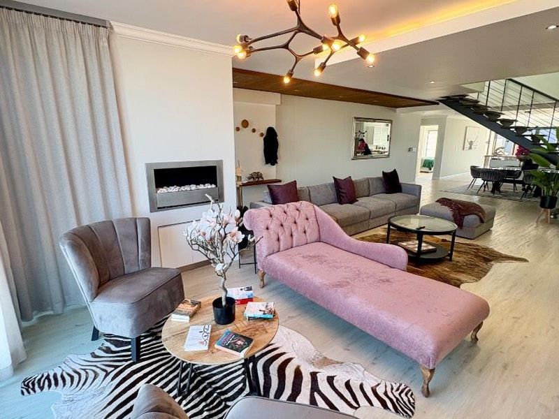 Spacious open-plan living area featuring a modern built-in fireplace, contemporary light fixtures, and a staircase leading to the upper level.