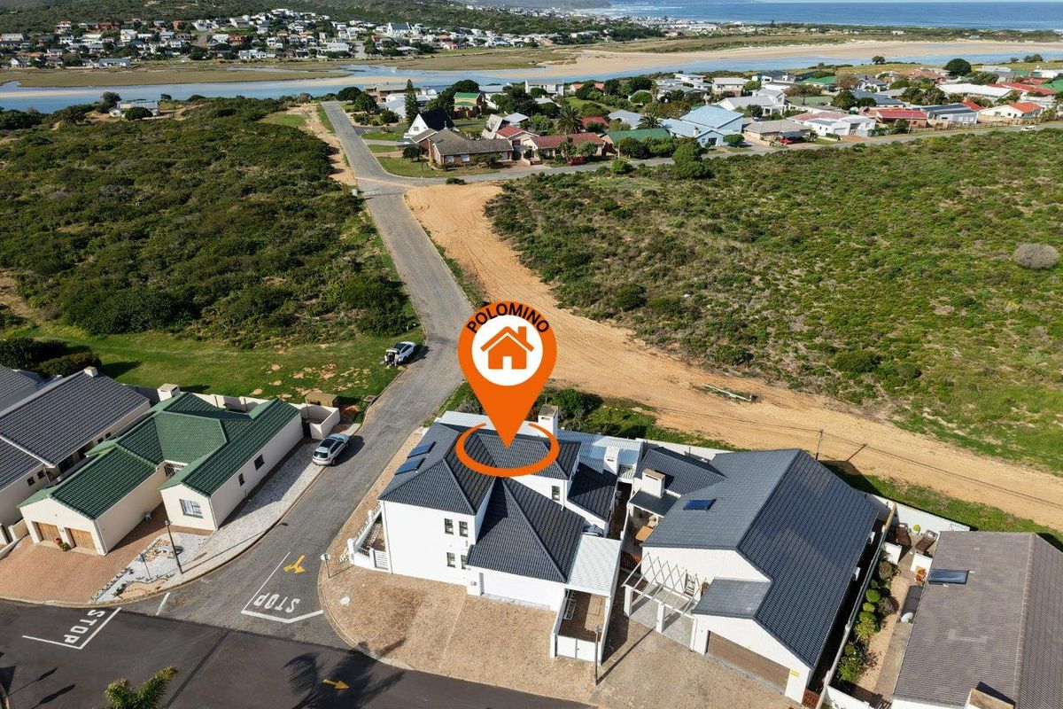 Aerial view of the property showing the roof structure, solar panels, driveway, and surrounding coastal neighbourhood landscape.