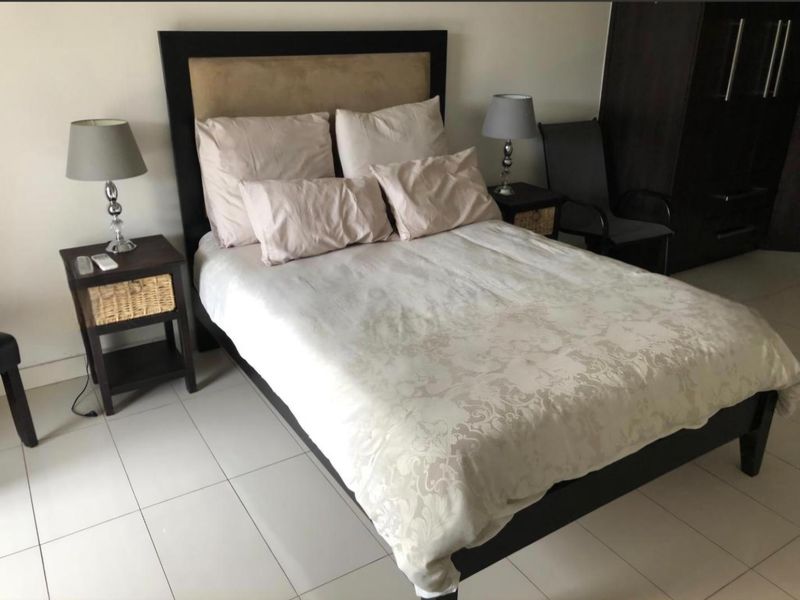 A functional bedroom featuring tiled flooring and a built-in wardrobe, providing a clean and neutral space for rest.