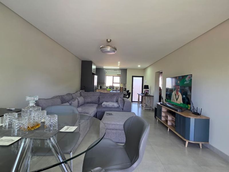 Spacious open-plan living and dining area featuring neutral tiled flooring, recessed lighting, and a seamless flow into the kitchen space.