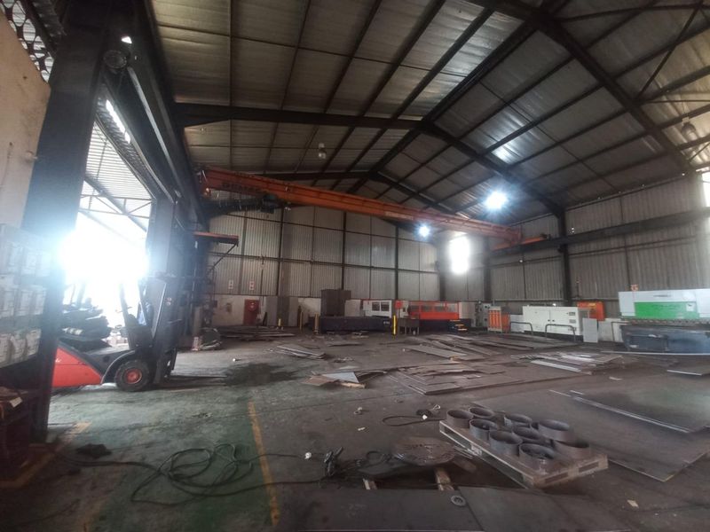 Spacious industrial warehouse facility featuring a high-clearance ceiling, integrated overhead gantry crane, and durable concrete flooring suitable for heavy manufacturing or storage operations.