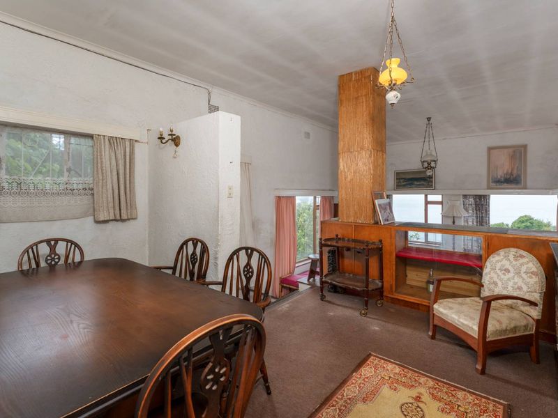 Spacious living area featuring textured walls, built-in timber cabinetry, and large windows with views, offering a dated interior ready for modern updates.