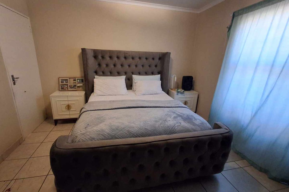 A bedroom featuring tiled flooring, neutral wall paint, and a window with sheer curtains.