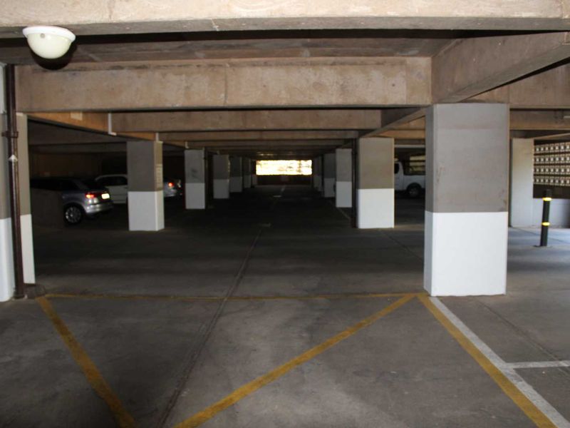 A covered, open-plan parking garage featuring concrete structural columns and beams with marked parking bays.