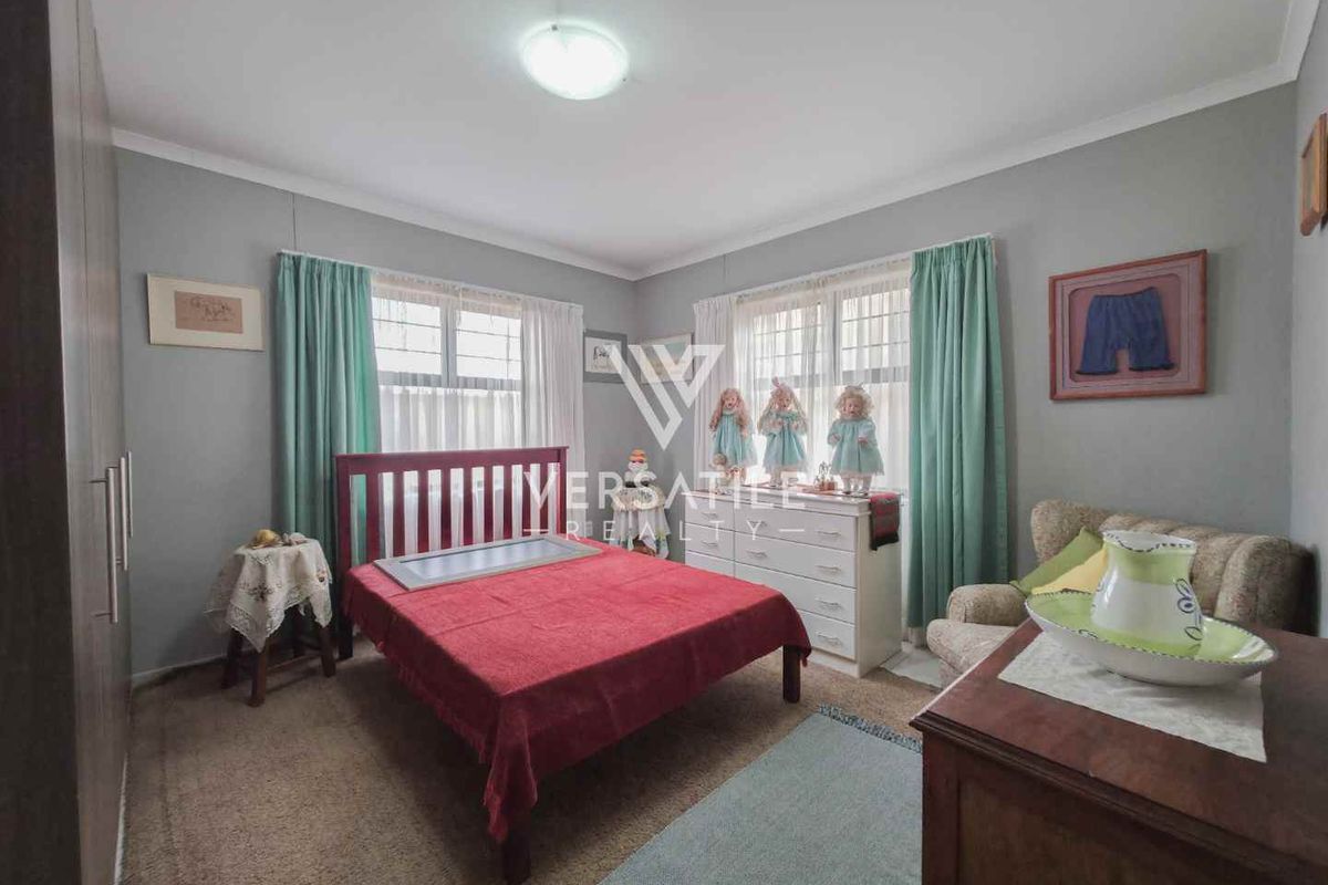 A well-proportioned bedroom featuring built-in cupboards, neutral wall finishes, and large windows that provide natural light.