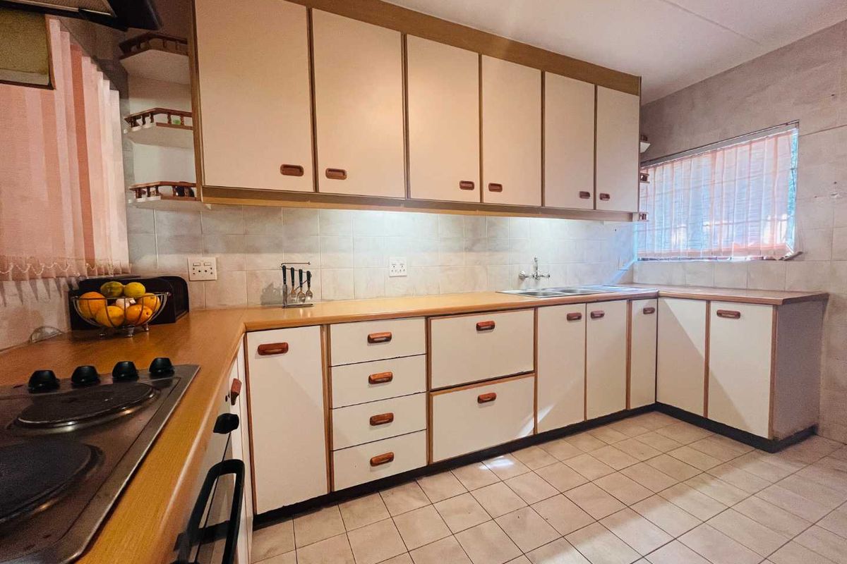 A functional kitchen featuring built-in cabinetry, a tiled backsplash, a double sink, and a built-in electric hob.