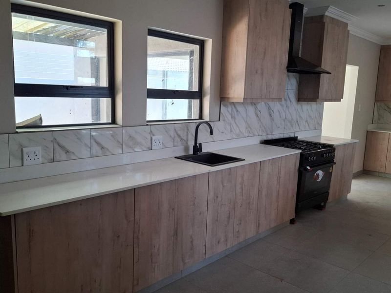 Modern kitchen featuring wood-look cabinetry, marble-effect splashback, quartz countertops, and a black gas stove with matching extractor hood.