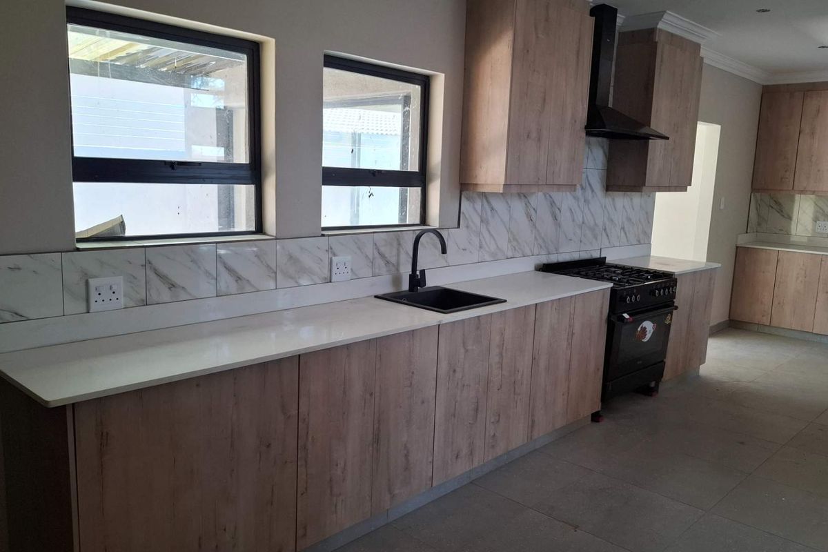 Modern kitchen featuring wood-look cabinetry, marble-effect splashback, quartz countertops, and a black gas stove with matching extractor hood.