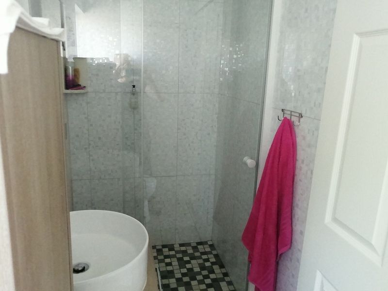 A compact bathroom featuring a glass-enclosed shower with mosaic floor tiling and a modern vessel sink vanity.