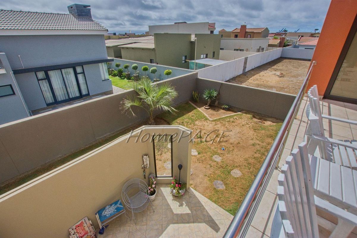 Elevated view of a private rear garden featuring a tiled patio area, perimeter boundary walls, and a lawned yard.