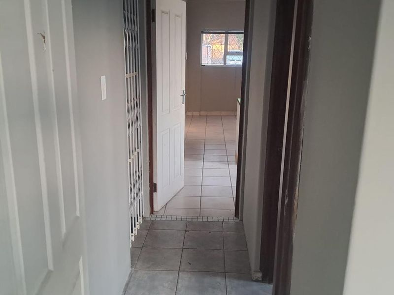 A functional hallway with tiled flooring and security gate, providing access to adjacent rooms within the apartment.