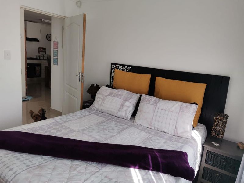 A bedroom featuring neutral walls and a doorway leading to an adjacent kitchen area.