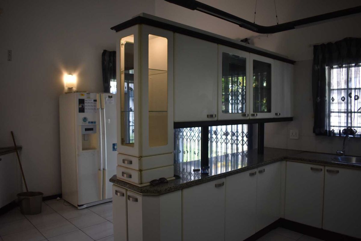 A kitchen featuring white cabinetry, granite countertops, and a built-in display cabinet, providing functional storage and workspace.
