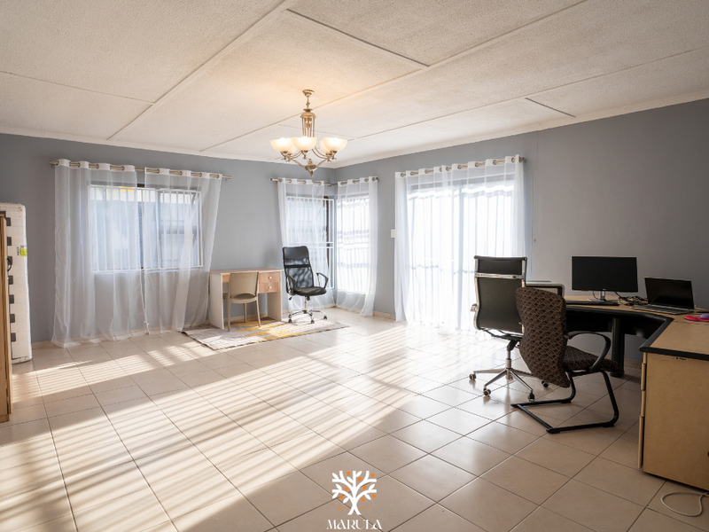 Spacious living area featuring tiled flooring, neutral grey walls, and sliding glass doors providing ample natural light.
