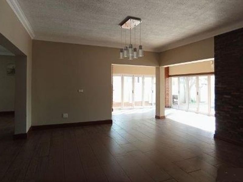 Spacious open-plan living area featuring tiled flooring, a striking stone feature wall, and large stacking doors that provide ample natural light.