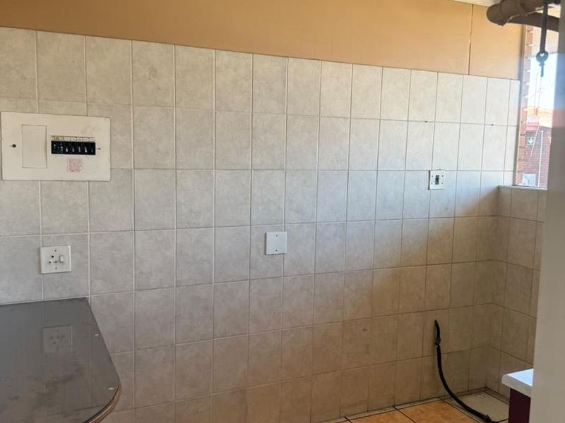A functional laundry area featuring tiled walls and flooring, with dedicated plumbing and electrical connections for appliances.