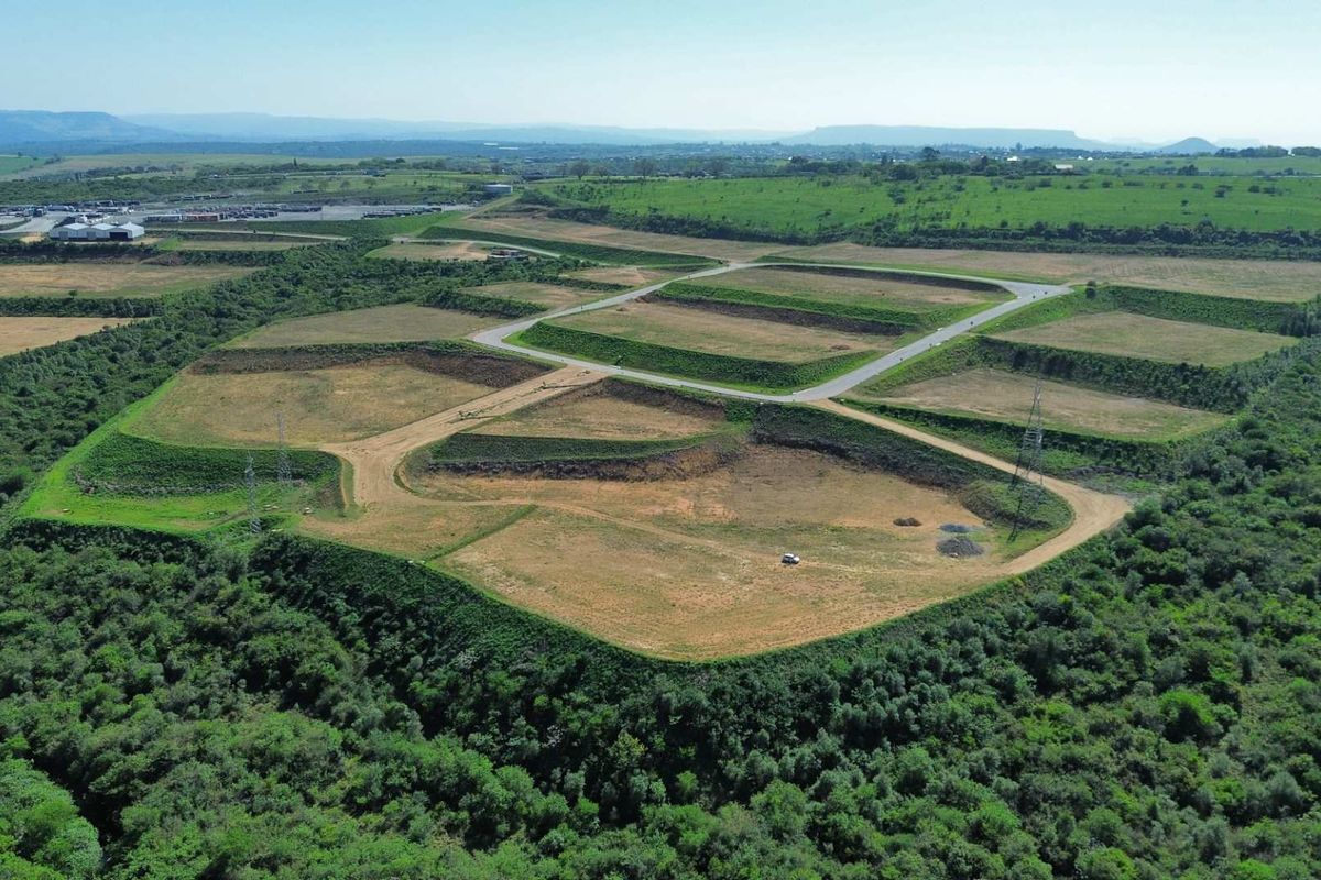 Aerial view of a large industrial development site featuring terraced plots, paved access roads, and surrounding natural vegetation.