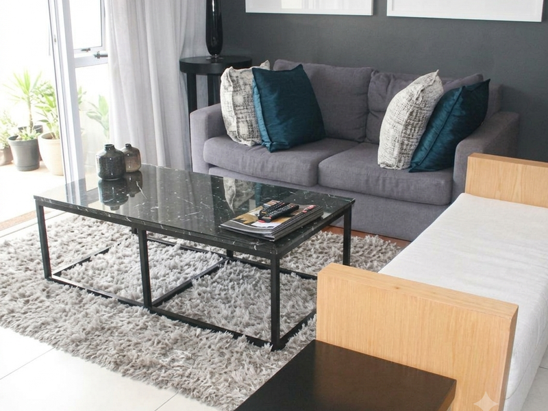A well-maintained living room featuring neutral tiled flooring and a sliding glass door providing access to an outdoor balcony area.