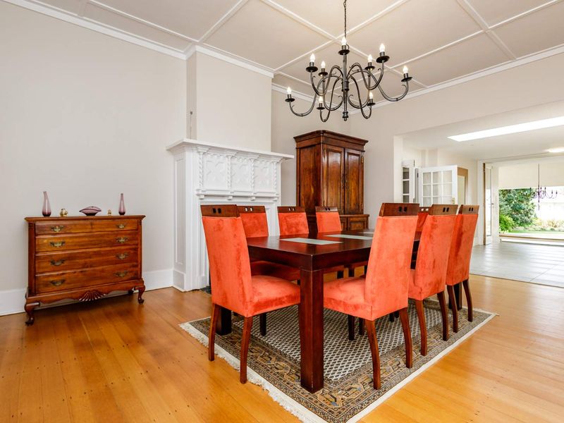 Elegant dining room featuring a classic fireplace mantel, coffered ceiling, and polished hardwood flooring, with direct access to an adjoining patio area.