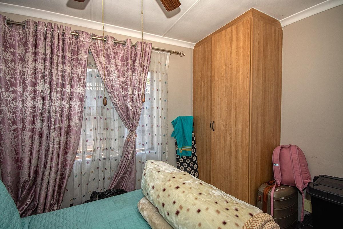 A bedroom featuring a built-in wooden wardrobe and a ceiling fan, providing functional storage and climate control.