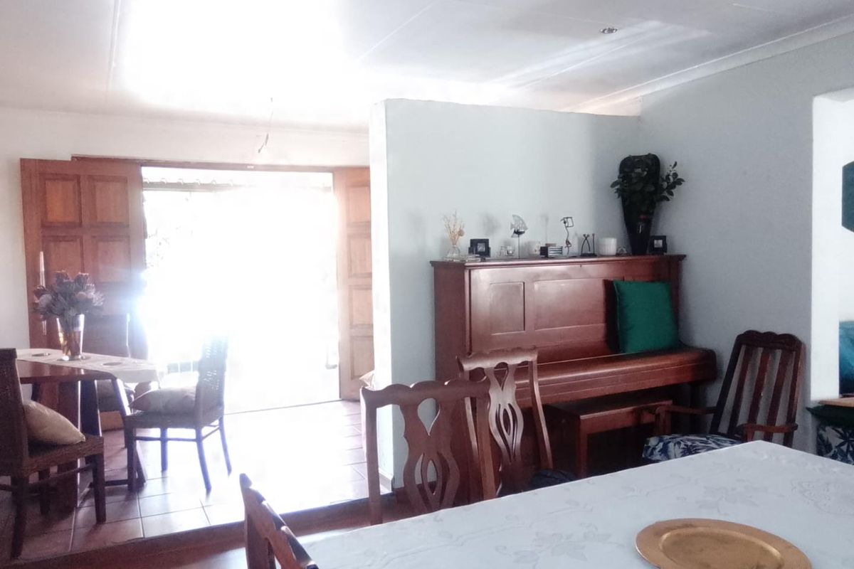 A living area featuring tiled flooring and wooden double doors leading to an outdoor space, with a coved ceiling and neutral wall finishes.