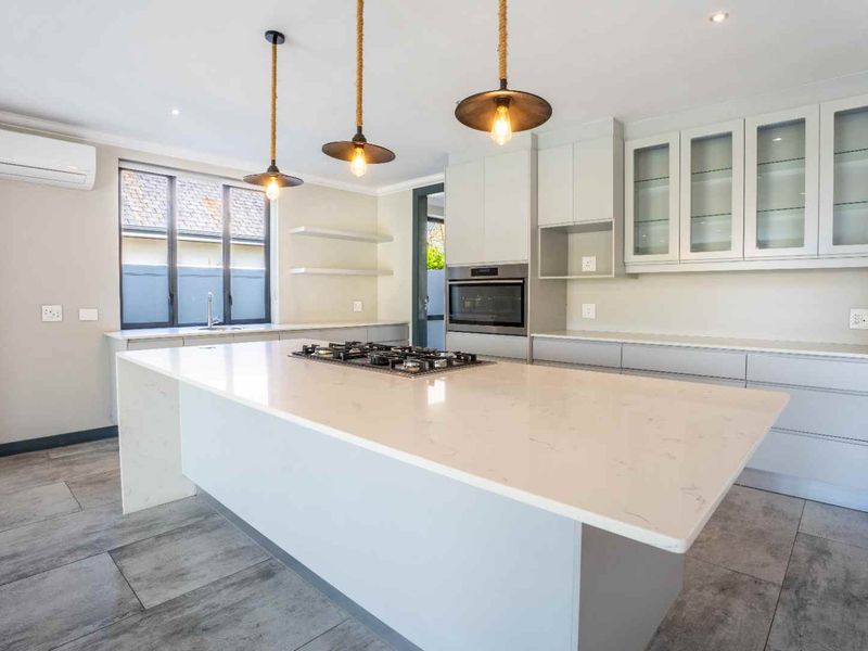 Modern kitchen featuring a large central island with a gas cooktop, stone countertops, ample cabinetry, and high-quality finishes throughout.