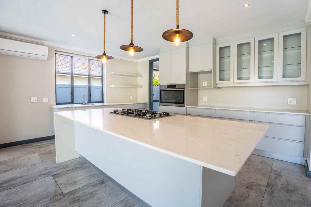 Modern kitchen featuring a large central island with a gas cooktop, stone countertops, ample cabinetry, and high-quality finishes throughout.