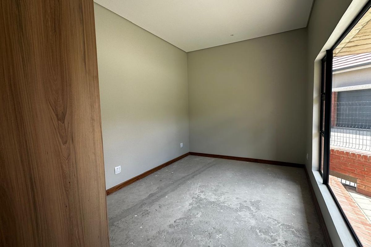 An empty bedroom featuring neutral walls, large windows, and an unfinished concrete floor, awaiting final flooring installation.