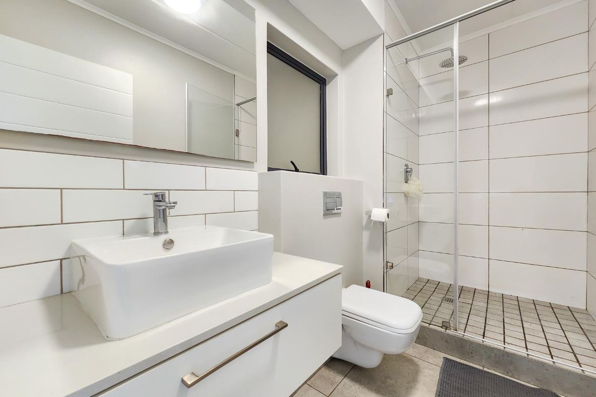 Modern bathroom featuring a wall-mounted vanity with vessel sink, wall-hung toilet with concealed cistern, and a spacious walk-in shower with glass enclosure.