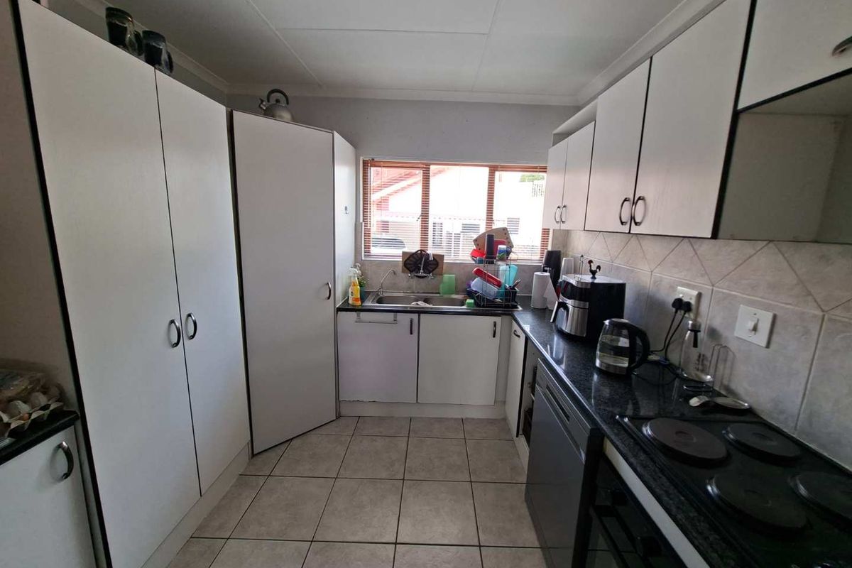 Functional kitchen featuring white built-in cabinetry, granite countertops, tiled backsplash, and integrated electric hob and oven.