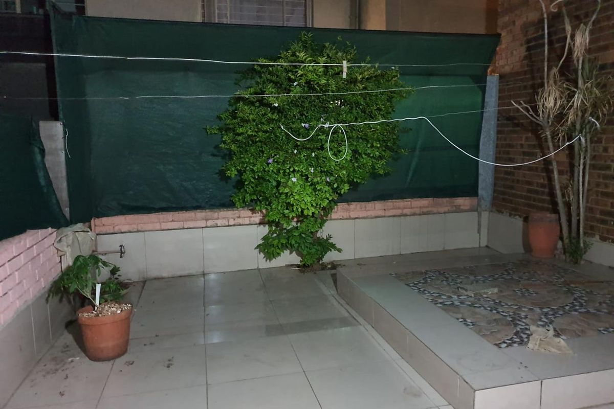 A paved rear courtyard area featuring a raised tiled platform, brick walling, and an outdoor water tap.