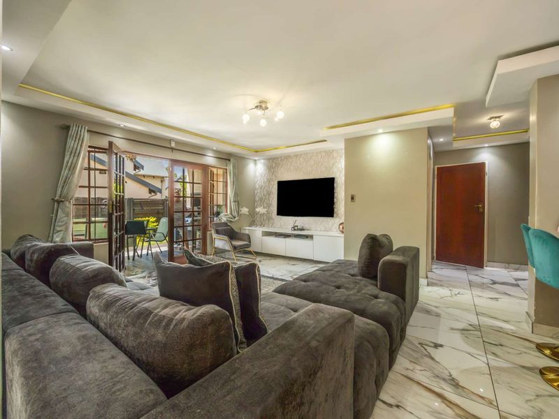 Spacious open-plan living area featuring marble-look flooring, recessed ceiling lighting, and direct access to an outdoor patio through classic french doors.