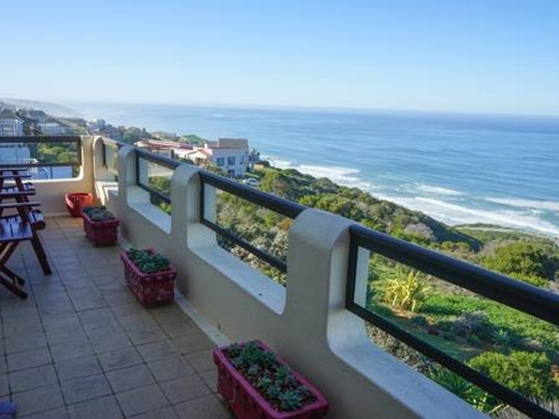 Spacious balcony featuring tiled flooring and a secure glass-paneled balustrade, offering expansive, elevated coastal and ocean views.