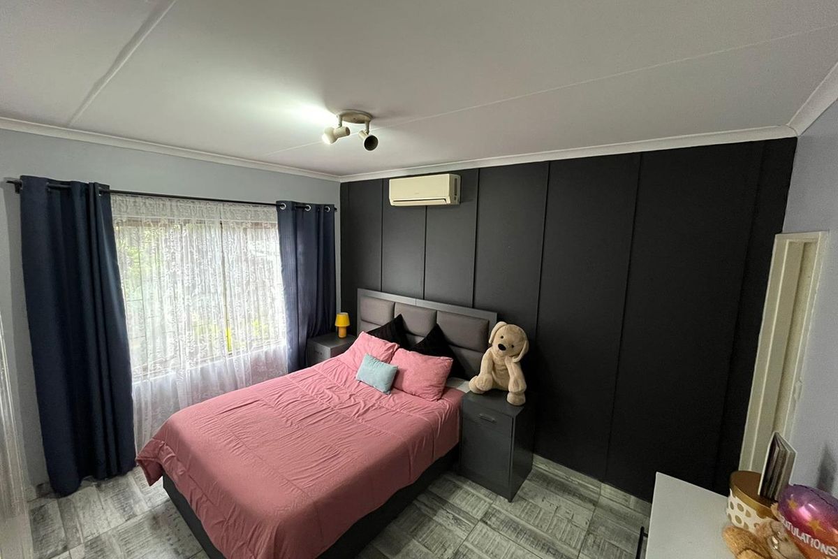A bedroom featuring tiled flooring, a split-system air conditioner, and a dark-toned built-in wardrobe wall.