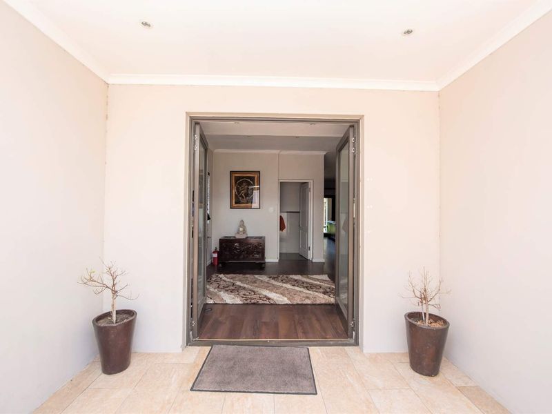 A welcoming covered entrance area featuring tiled flooring and double glass doors leading into the home's interior.