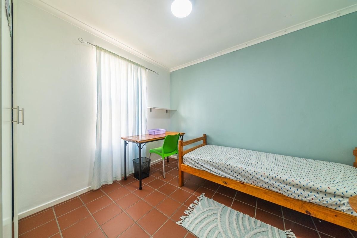 A functional bedroom featuring tiled flooring, a built-in wardrobe, and a neutral color palette with a soft blue accent wall.