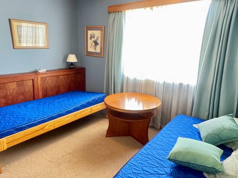 A bedroom featuring blue walls, crown molding, a ceiling fan, and carpet flooring, currently furnished with two single beds.