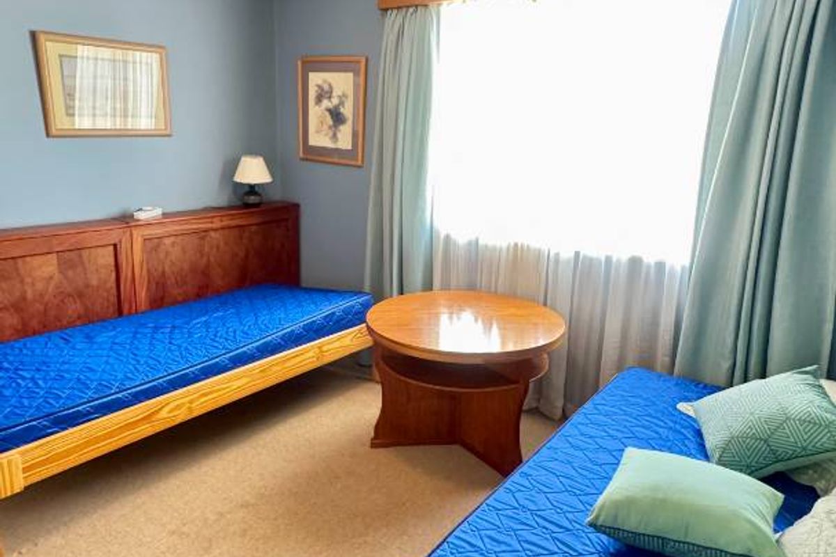 A bedroom featuring blue walls, crown molding, a ceiling fan, and carpet flooring, currently furnished with two single beds.