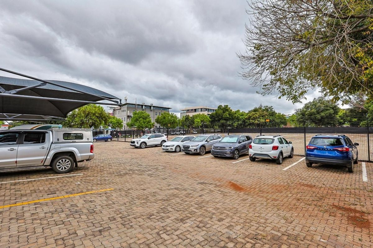 A paved outdoor parking area featuring marked bays and a shade cloth structure for vehicle protection.